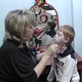 Логопед делает массаж щек у ребенка